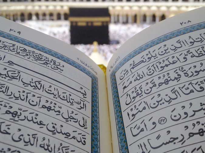 Open Quran with Kaaba in the background